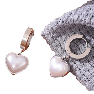 Elegant heart-shaped pearl earrings with silver hoops on a textured grey background