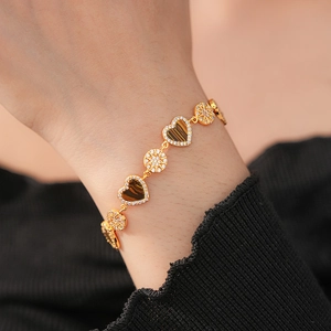 Detail of 18K gold plated bracelet with heart tiger eye stones and zircon floral elements