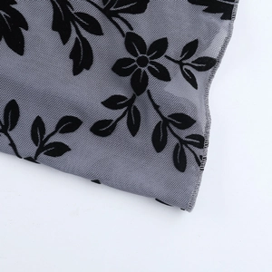 Detail of grey mesh fabric featuring black flocked floral patterns and sheer texture