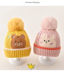 Detail of knitted baby hats featuring cute animal patches and large pom-poms on top