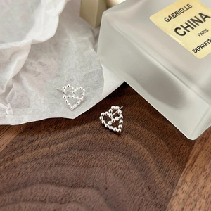 Macro shot of 925 sterling silver heart earrings with beaded hollow design on paper