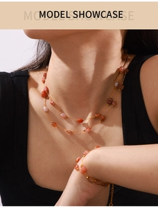 Detailed view of layered gold necklace and bracelet set with orange agate beads on a model