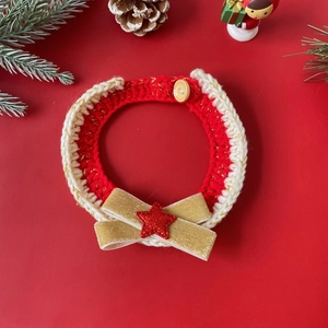 Detail of red and white knitted Christmas pet collar with gold bow and star decoration