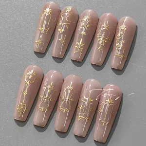 Detail view of long ballerina press-on nails with matte pink base and gold relief patterns