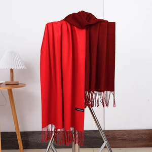 Detail of red and burgundy cashmere scarf featuring a classic fringe edge and logo label