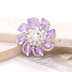 Vista detallada de broche floral con cristales violetas y perlas blancas elegantes
