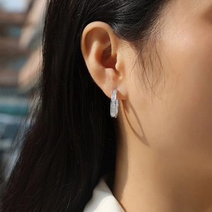 Close-up of silver C-hoop earrings with double row moissanite on model ear