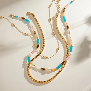 Detail of layered gold cuban chain and multi-colored natural stone bead necklace set