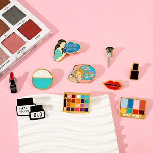Detailed close-up of makeup-themed enamel pins including eyeshadow and lipstick designs