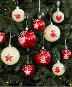 Close-up of red and cream Christmas baubles with star and heart patterns on tree