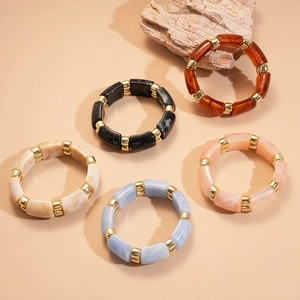 Close-up of geometric acrylic bracelets in various colors with golden spacers