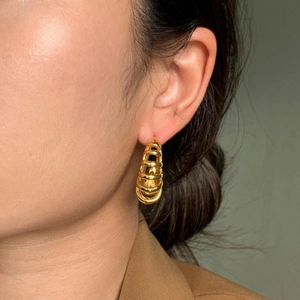 Detail view of model wearing 18k gold plated chunky layered hoop earrings with textured finish