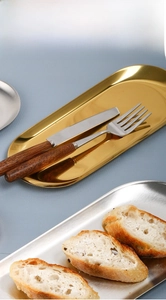 Oval stainless steel serving tray with polished gold and silver finishes in a table setting
