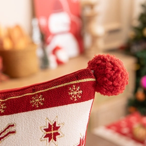 Detail of red and white Christmas runner with gold snowflake embroidery and a plush pompom