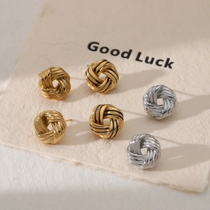 Three pairs of twisted knot stud earrings in gold and silver finishes on textured card