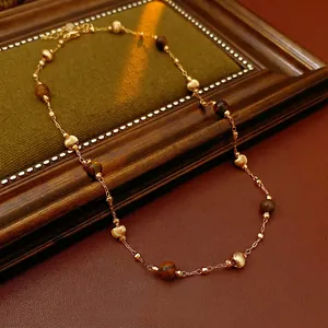 Gold plated tiger eye beaded necklace on green velvet tray with vintage aesthetics