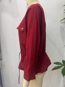 Detailed side view of a red linen-blend safari jacket featuring drawstring waist and buttons