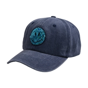 Detail of sequined smiley face patch on a dark blue washed vintage baseball cap