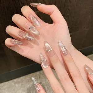 Detail of almond cat eye press-on nails with 3D floral accents and shimmering rhinestones
