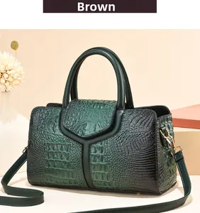 Detail of dark green crocodile texture handbag with gold hardware and stitching