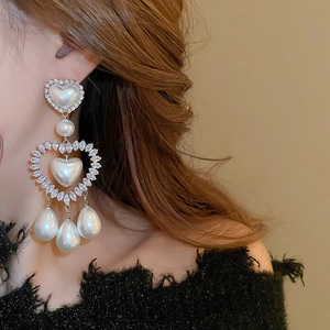 Dettaglio di orecchini d'argento con perle a cuore e goccia su una modella