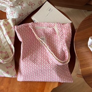 Sac fourre-tout en toile blanche à motifs nœuds rouges et lanières sur table en bois