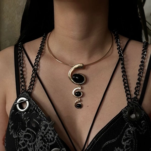 Close-up of golden collar necklace with three vertical black oval resin pendants on model