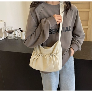 Detail of cream pleated hobo bag featuring a drawstring pocket and durable fabric texture
