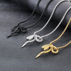 Macro view of punk style snake pendants in gold, silver, and black finish on a dark base