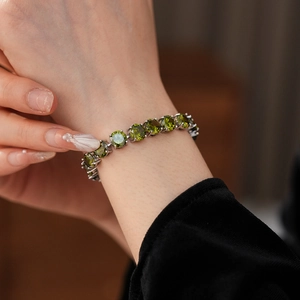 Detail view of round cut olive green gemstone tennis bracelet with silver prong setting