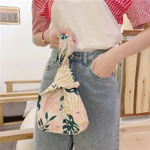 Close-up of tropical leaf print on linen wrist bag featuring a knot handle design