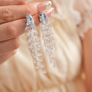 Close-up of diamond-shaped zircon earrings with long clear crystal tassels on silver pins