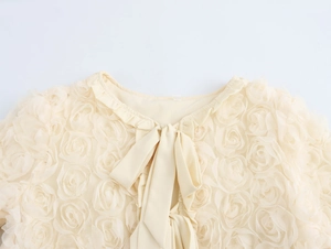 Detailed close-up of beige cardigan featuring 3D rose texture and bow tie neckline