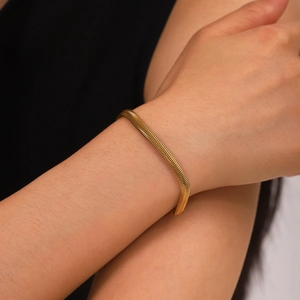 Close-up of 18k gold plated herringbone snake chain bracelet on a woman wrist