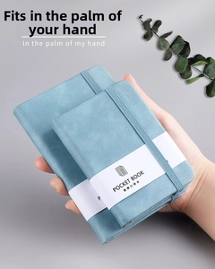 Close-up of a person holding a portable light blue leather notebook with elastic band