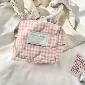 Detail view of pink and white checkered quilted fabric and branded cloth label on the pouch