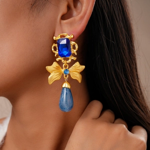Vintage baroque earrings with blue sapphire drop and gold bow on a female model