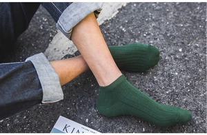 Detail of dark green ribbed cotton ankle socks worn with blue jeans on an asphalt path