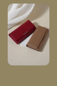 Detail of red and camel long leather wallets with secure buckle closures on white podium