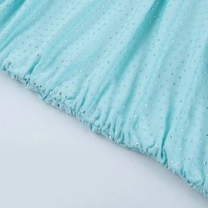 Close-up of light blue pleated fabric with shimmering silver polka dots on the dress