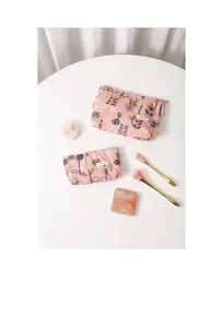 Flat lay of pink floral embroidery cosmetic bags with gold leaf details and makeup accessories