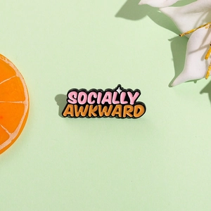 Enamel Socially Awkward pin badge with pink and orange colors on green paper background