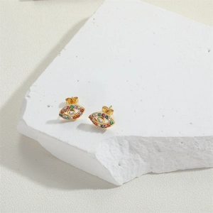Detail of evil eye stud earrings with colorful zircons on golden metal base