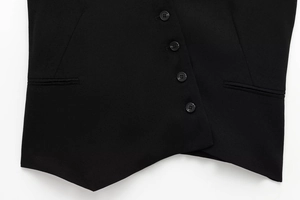 Detail of black asymmetrical vest featuring four buttons, side pockets and premium fabric