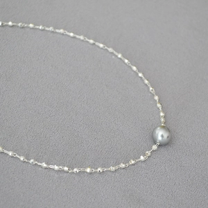 Macro detail of faceted gold beads and white pearl on minimalist brass choker necklace