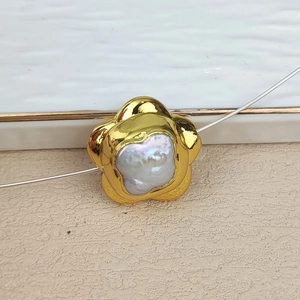 Macro view of gold-plated flower pendant with a natural irregular freshwater pearl center