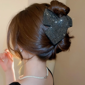 Detail showing high-end black bow hair claw clip with golden rhinestones on brown hair