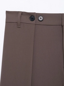 Detail of brown trousers featuring double-button closure and diagonal twill fabric texture