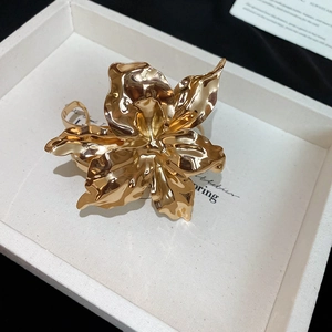 Detailed close-up of golden flower arm cuff featuring a mirror-polished liquid metal finish