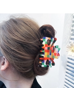 Detail showing a colorful checkered hair claw clip with heart cutout on a hair bun
